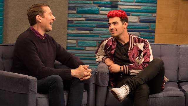 Joe Jonas Wears a Maroon and Gold Letterman Jacket With White Sneakers